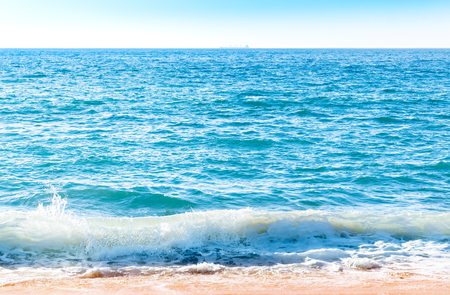 Ocean wave with foam coming to the sand beachの写真素材