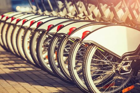 Wheels of bicycles at rental station at sunset