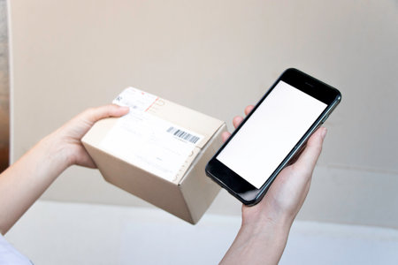 Right hand holding smartphone for your mockup,cardboard boxの写真素材
