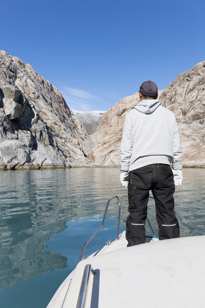 young man stand on board sailing to mountain icecap glacier narsaq greenlandの写真素材