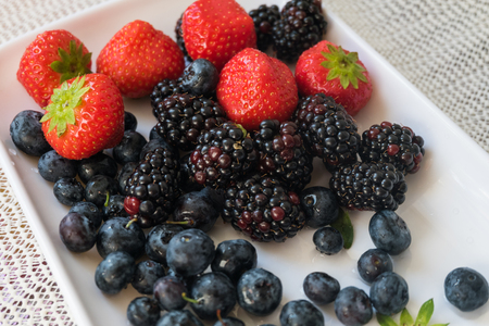 mix berry strawberry blackberry blueberry with red black blue. food flesh berry from nature with green leaf on white plate ready to eat.の写真素材