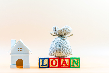 Home model and money bag put on wooden block cube business loans for real estate concept.の写真素材