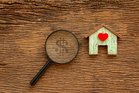 Home model with red heart and a magnifier with searching for money put on the vintage wood background, Loan for real estate or saving money for buy a new house to family in the future concept.の写真素材