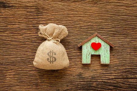 Home with red heart model and a big money bag put on the vintage wood background, Saving money for buy a new house or loan for plan business investment of real estate concept.の写真素材