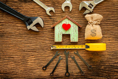 Wooden house with red heart and wrench and money bag put on the old wood, Loan for construction real...