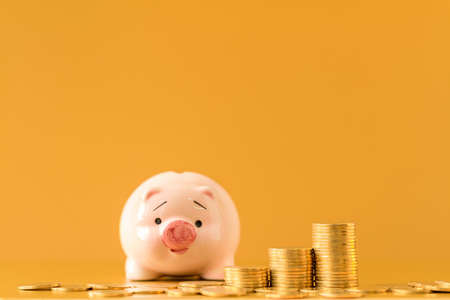 A piggy bank and stacked gold coin with growing valueof deposit put on the desk in the office ,...