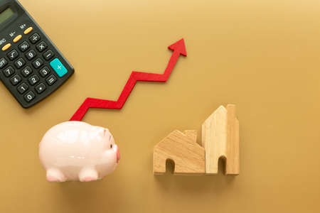 Piggy bank and home and red arrow graph with growing value on brown background, for currency and financial business investment and fund real estate concept.の写真素材