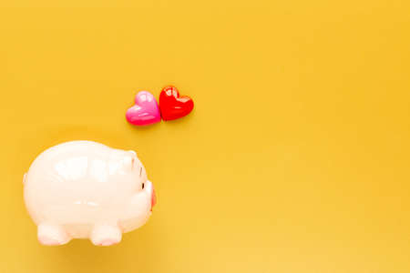 A piggy bank and red and pink heart put on the brown background and copy space for ad text, the saving for loved one and planned investment in the future concept.の写真素材