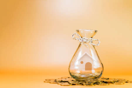 Loan or saving money for buy a house and real estate for family concept, Home model put inside the jar put on the coin with growing business investment on the brown background.の写真素材