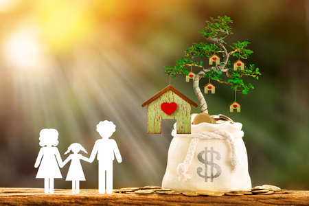 Family with paper art and coin in a money bag and grow to a tree produce house put on the wood, Save money or loan for business investment real estate of owner in the future and buy a new home conceptの写真素材