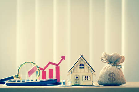 Money bag and home model and red bar graph with growing value  in the office, Loan for real estate to family in the future concept.の写真素材