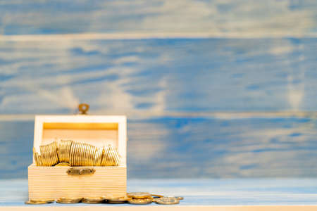 Gold coin in the wooden box with grow interest and value on the vintage blue background, Saving...