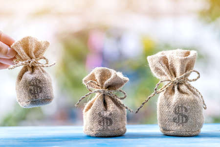 Man hands hold  for select a money bags put on the vintage blue wooden board  in the public park,...