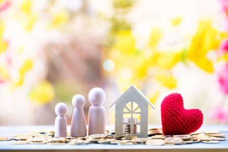 Home and stack gold coin with growing value money and light bulb and red heart and family put on the wood in the public park, Idea of investing in buying a real estate or decorating a house concept.の写真素材