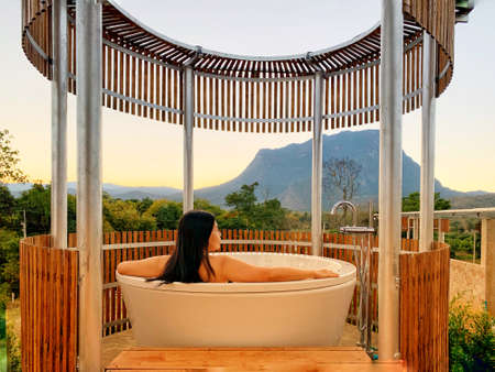 asian waman relaxing and spa in the bathtub in outdoor bathroom is surrounded by nature background...