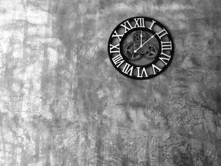 Industrial style wall clock with roman numbers on ten on a Concrete Wall with Room for Copy,decorative clock steampunk style  made in metal over a concreat  wall loft stye.の写真素材