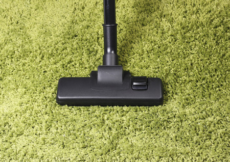 Vacuum cleaner head on green carpet