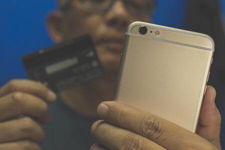 Asian man holding credit card and smartphone to payment shopping onlineの写真素材