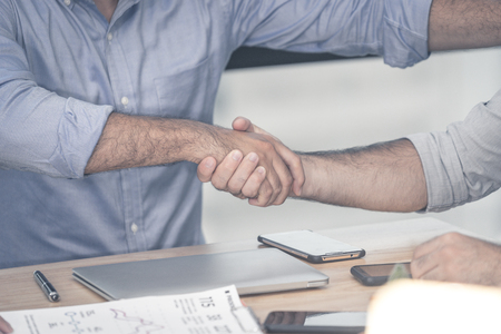 Business man shaking hands on office desk close-up at handsの写真素材