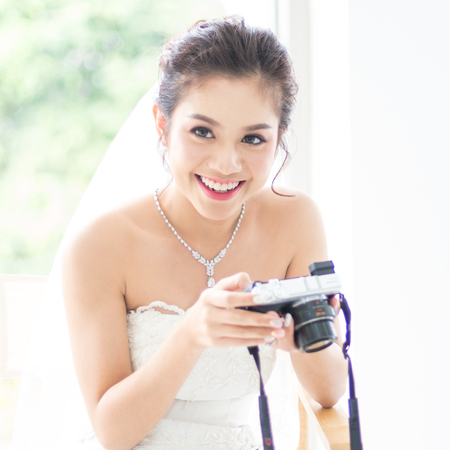 Thai Bride in White dress looking pictures from camera of wedding photographerの写真素材