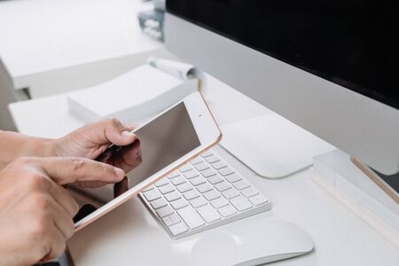 Man holding smart phone with computer desktop in office with Vintage toneの写真素材