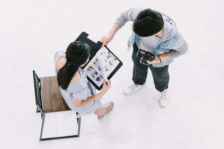 Asian Photographer taching and shooting with female model reading magazine in Studio with studio strobeの写真素材