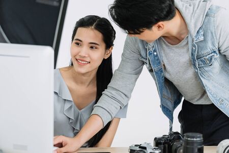 Model and Photographer looking pictures from monitors computer and choosing the right picturesの写真素材