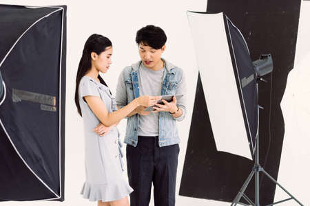 Asian Photographer and model looking pictures from tablet with White backgroundの写真素材