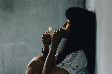 Asian woman smoking cigarette In a dim atmosphere Hold the lighters in the hand to light the cigaretteの写真素材