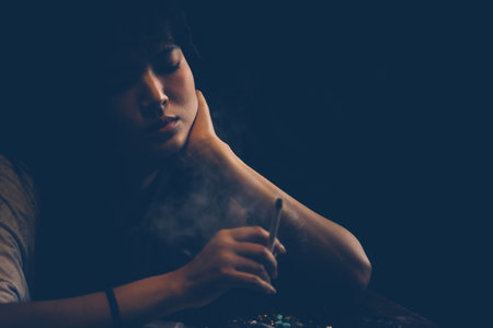 Asian woman smoking cigarette In a dim atmosphere Hold the lighters in the hand to light the cigaretteの写真素材