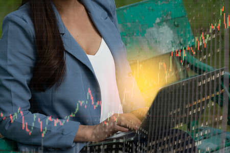 Thai Business Woman typing on Laptop keyboard to working and sitting on the bench in public parkの写真素材