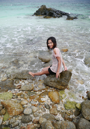 asian woman relax on the rock by the beach