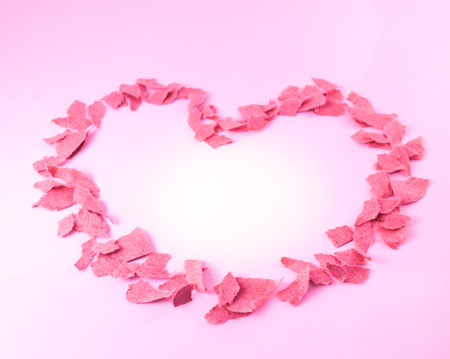 Heart shape from pieces of paper in pink toneの写真素材