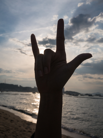 silhouette hand  symbol of love on evening sunset at beachの写真素材