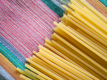 Raw yellow pasta spaghetti on fabric textile background