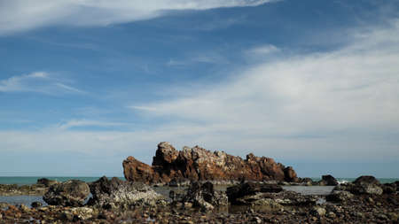 Coast of the sea with rocks and a blue sky with cloudsの写真素材
