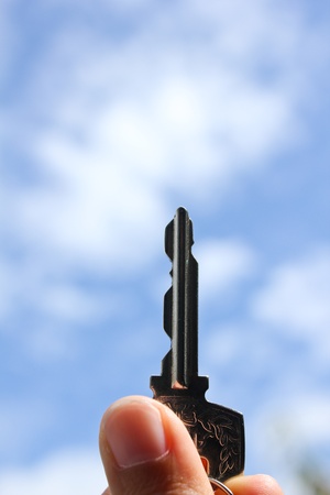 Hand holding keys,blue skies in the backgroundの写真素材