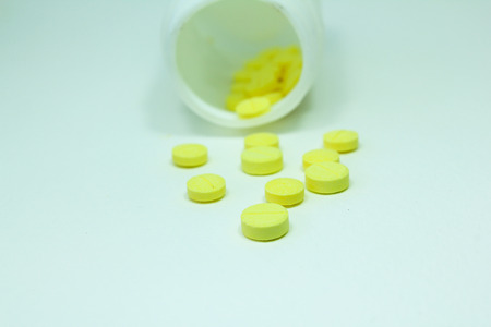 pills and pill bottle-Prescription pill bottle spilling pills on to surface isolated on a white backgroundの写真素材