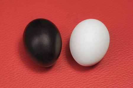 Black and white chicken eggs on a red backgroundの写真素材