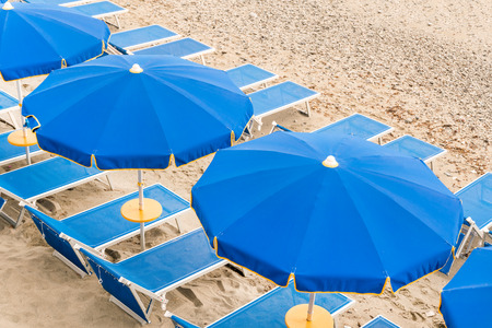 Blue empty sunbeds with umbrellas on the beachの写真素材