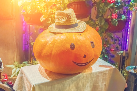Halloween pumpkin with painted face in a straw hatの写真素材