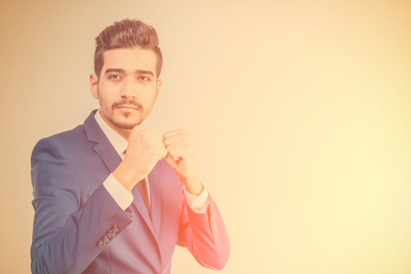 Young attractive man in a blue suit showing punch gesture in the sunlight . Tonedの写真素材