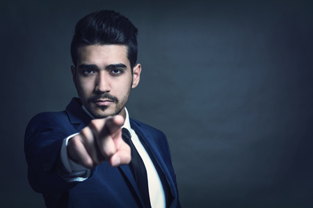 Young attractive man in a blue suit showing a finger forward. Tonedの写真素材