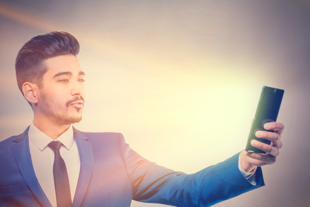 Young attractive man in a blue suit with phone emits light. Tonedの写真素材