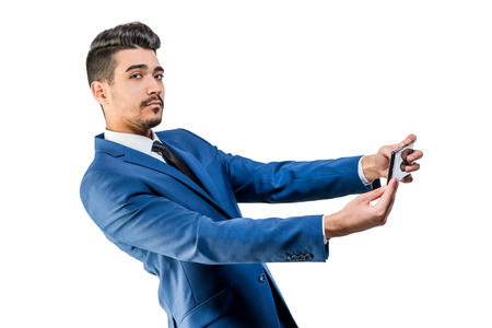 Young attractive man in a blue suit with phone on a white background. Isolatedの写真素材