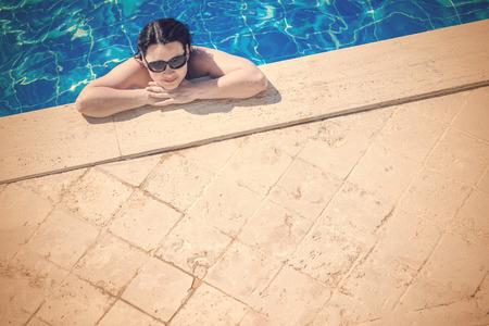 Woman in sunglasses near the pool edge, top viewの写真素材