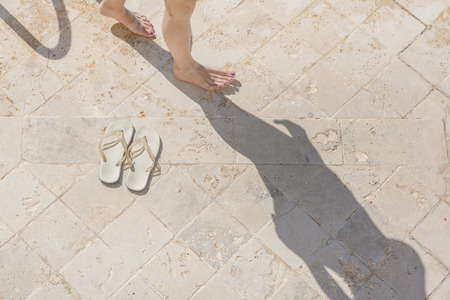 White sandals and female legs on the tileの写真素材