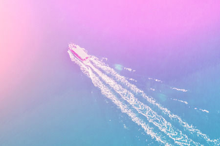 Top view of a white boat sailing in the blue sea on a sunny dayの写真素材