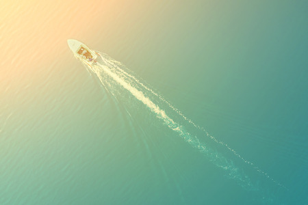 Top view of a white boat sailing in the blue sea on a sunny dayの写真素材