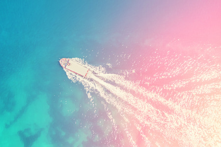 Top view of a boat floating on the blue sea in the sunlightの写真素材